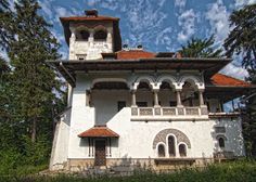 an old white building sitting in the middle of a forest