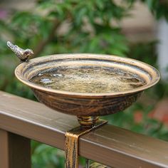 a bird is sitting on the edge of a bowl that has water running down it