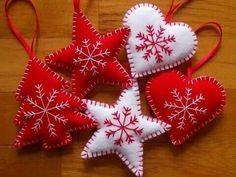 four red and white ornaments hanging on a wooden floor with snowflakes in the shape of hearts