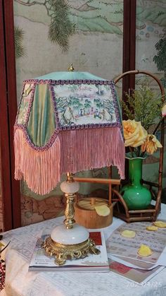 a table topped with a lamp next to a green vase