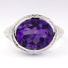 This vintage style ring features a bright purple amethyst set in a sterling silver setting. The Art Deco style setting is beautifully crafted with an east west bezel setting and curling filigree details. The amethyst is a natural, earth mined stone. The ring measures 12.8mm across (north south) and 6mm from finger to top. Please note that colors can vary slightly depending on your monitor and display settings. The video shows this ring with a swiss blue topaz center and is meant to display the d Amethyst Set, Vintage Style Rings, Amethyst Color, North South, Bright Purple, Swiss Blue Topaz, Natural Earth, East West, Ring Vintage