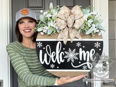 a woman holding up a welcome sign in front of a door