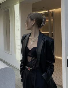 a woman in a black suit is walking down the street with her hand on her hip