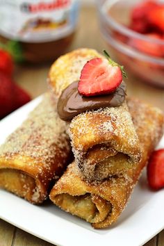 some strawberries and chocolate covered pastries on a white plate