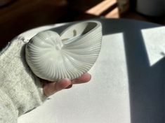 a person holding an object in their hand on top of a white cloth covered table