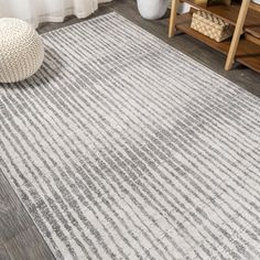 a white and gray rug with vertical stripes on the floor in front of a window