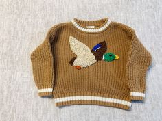 a brown sweater with a bird on it