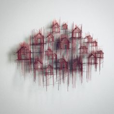 an abstract painting with red lines and houses on the white wall in front of it