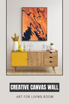 a living room with an orange and black painting on the wall next to a yellow dresser