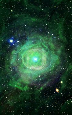 an image of a green spiral in the middle of space with stars and dust around it