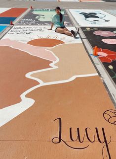 a woman sitting on the ground next to a mural