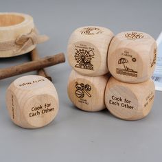 four wooden dices with different designs on them and an empty bowl in the background