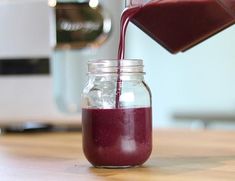 a glass jar filled with red liquid being poured into it