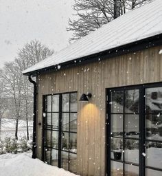 a small wooden building covered in snow with lots of windows and lights on the side