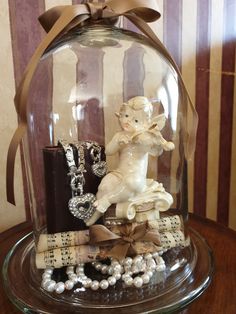 a glass cloche with an angel figurine under it on top of a table