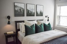 a bed with white sheets and green pillows next to two framed pictures on the wall