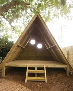 a small wooden structure with two round lights in the roof and steps leading up to it