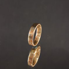 two wedding rings sitting on top of a black surface next to each other with gold flecks