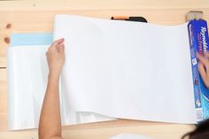 a woman is making a piece of paper on the table with scissors and glue in her hand