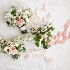 three bouquets of flowers are laid out on a bed sheet with pink and white ribbons