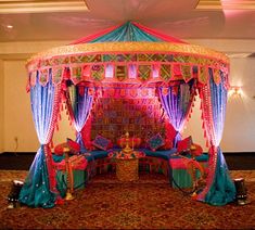 an elaborate bed with blue and pink drapes on the top is set up for a wedding