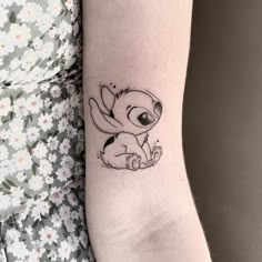 a woman's arm with a small tattoo of a cartoon character on the wrist