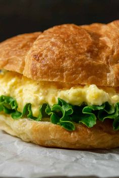 an egg salad sandwich with lettuce and cheese on croissant buns