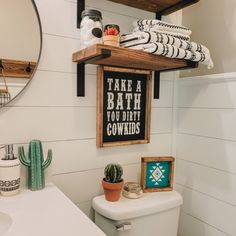 a bathroom with a toilet, mirror and shelf above it that says take a bath you don't cowboys