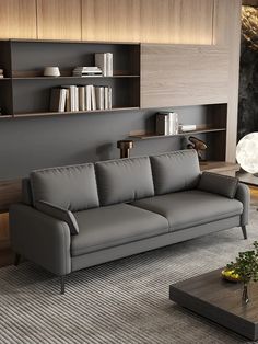 a modern living room with grey leather couches and bookshelves on the wall