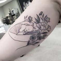 a woman's arm with flowers and leaves on it