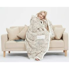 a woman sitting on top of a couch covered in a blanket