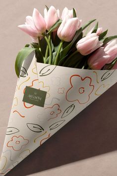 a bouquet of pink tulips in a paper cone with a name tag on it