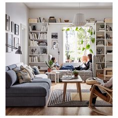 a living room filled with lots of furniture and bookshelves next to a window