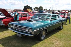 several classic cars are parked on the grass at a car show, with people standing around