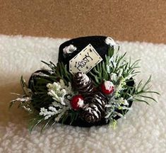 a black hat with pine cones and white flowers on it sitting on top of a blanket