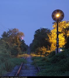 an old railroad track is lit up by the light of a street lamp at night