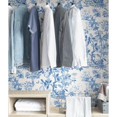 clothes hanging on hooks in front of blue and white wallpaper