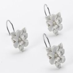 three pairs of earrings with white flowers and silver hooks on the earring wires, all in different shapes and sizes