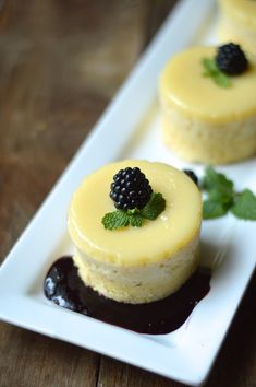 two small desserts on a white plate with blackberries and mint garnish