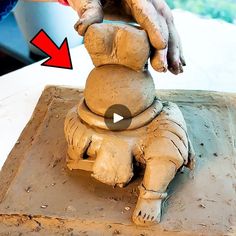 someone is making a statue out of clay with one hand and the other arm extended