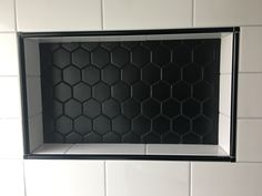 a black and white tiled bathroom with hexagonal tiles on the wall above it