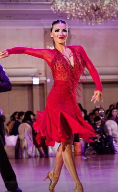 a woman in a red dress dancing with a man in a suit and tie behind her