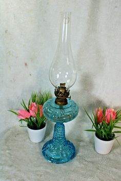 three small potted plants are sitting on a blue pedestal with a light bulb in the middle