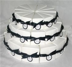 three tiered cake with black and white ribbon on it's sides, decorated with shark silhouettes