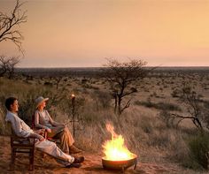 two people sitting around a campfire in the desert