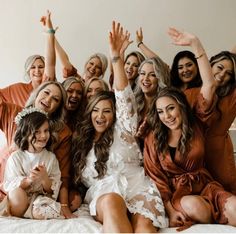 a group of women sitting on top of a bed posing for the camera with their arms in the air