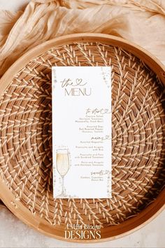 the menu card is placed on top of a wicker plate with a glass of wine