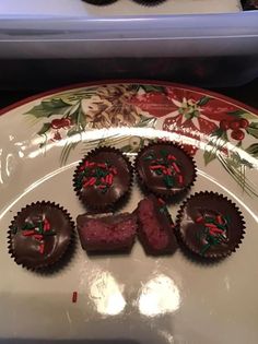 some chocolates are on a plate with holly decorations and red berries around the edges