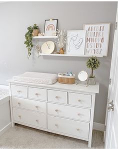 a baby's room with white furniture and pictures on the wall