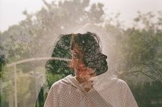 a woman standing in front of a window with her face obscured by the sun's rays